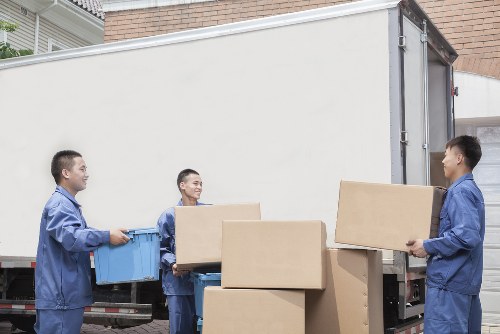 Movers carrying furniture through a West Brompton property entrance